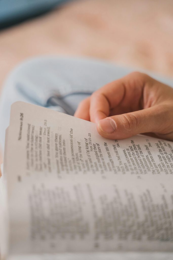 Hand of a Person Holding a Page of the Bible that they are reading