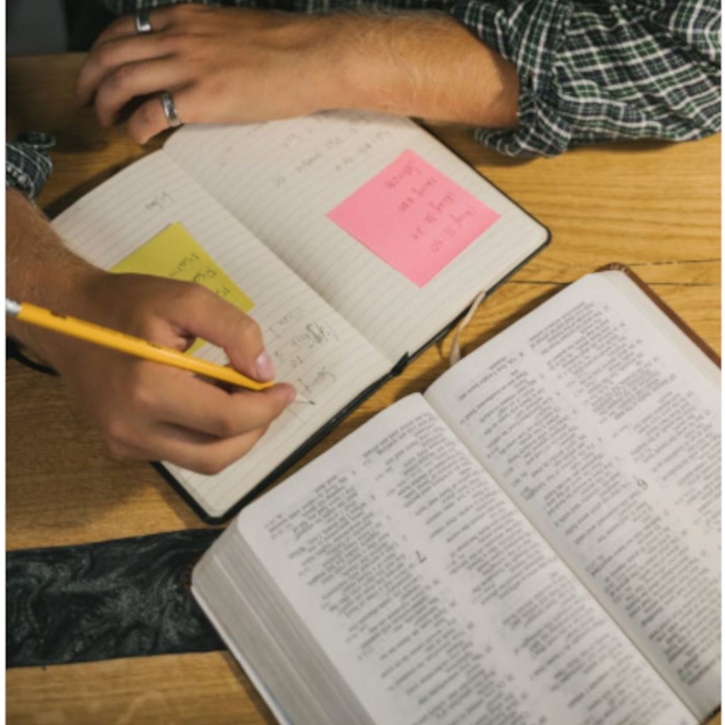 Close-up of Bible text and a man Bible Journaling in his notebook
