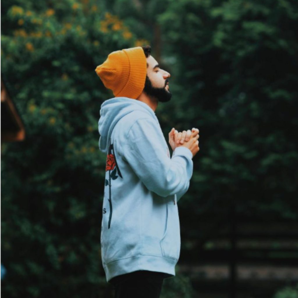 A man standing in nature praying and listening for the Lord's response
